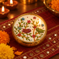 Bird Motif Soy Wax Candle in a Brass Urli, 4 in, lit for Diwali on a mirror-work runner