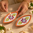 Boat-Shaped Pressed-Flower Terracotta Diyas, being lit by hand