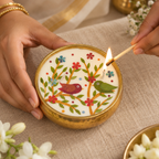 Bird Motif Soy Wax Candle in a Brass Urli, 4 in, being lit by hand